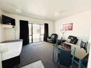a room with a bed and a table and chairs at ASURE Phoenix Motor Inn in Blenheim