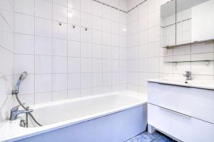 a white bathroom with a tub and a sink at Canal de Yvette in Longjumeau