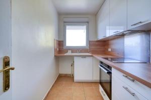 a kitchen with white cabinets and a sink and a window at Canal de Yvette in Longjumeau