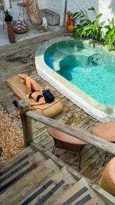 a woman laying on a towel next to a swimming pool at Pousada Villa Cacau in Trancoso