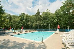 a large swimming pool with white chairs at 4BD Cabin in the Poconos Near Lake with Hot Tub, Sauna, Game Room and Movie Room in East Stroudsburg