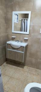 ein Badezimmer mit Waschbecken, Spiegel und Toilette in der Unterkunft CasaMar in General Villegas + 2 Fotos