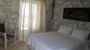 a bedroom with a white bed and a stone wall at Milo Milo Suites in Mandrakia