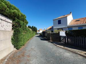 a residential street with a fence and a house at Maisonnette confortable proche plage, 4 pers, parking privé - FR-1-476-203 in La Faute-sur-Mer