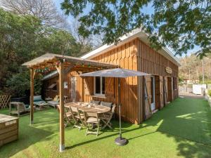 ein Haus mit einem Tisch und einem Sonnenschirm im Hof in der Unterkunft Maison à Biscarrosse: 8 pers, piscine, clim, proche lac et pistes cyclables, ménage inclus - FR-1-319-538 in Biscarrosse