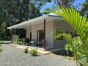 Una pequeña casa blanca con un patio y una palmera. en Casa Andersson - Your Caribbean House with Pool, en Puerto Limón