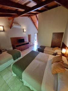 a hotel room with two beds and a television at Hotel Blumig in Villa General Belgrano