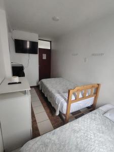a hotel room with two beds and a television at Hotel Ernesto in Casma