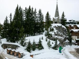une personne faisant du snowboard dans la neige à côté d'une église dans l'établissement Appartement Chaleureux à Courchevel 1850 - 3 Chambres - FR-1-613A-12, à Courchevel 6 autres photos