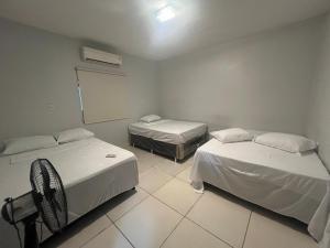 a room with two beds and a fan in it at Casa para eventos e acomodações in Goiânia