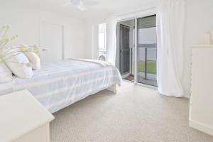 a white bedroom with a bed and a large window at River Shack Ballina  +34 photos