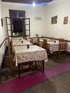 a dining room with tables and chairs and a flat screen tv at HOTEL PENSÃO COLONIAL - Centro Atibaia in Atibaia
