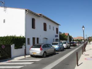 Une rangée de voitures garées à côté d'un bâtiment blanc dans l'établissement Appartement calme pour 4, avec terrasse et WIFI, Saintes-Maries-de-la-Mer - FR-1-475-211, à Saintes-Maries-de-la-Mer