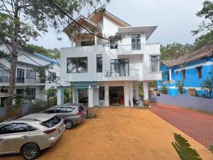 a white house with two cars parked in front of it at HeniSi Hotel Măng Đen (HeniSi 2) in Kon Von Kla