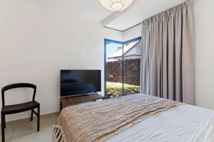 Un dormitorio con una cama, un televisor y una silla. en Spacious 3BR Oceanfront Retreat Paea Tahiti, en Paea 44 fotos más