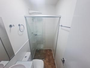a bathroom with a glass shower and a toilet at Studio tipuana, varandinha aberta com rede in Brasilia