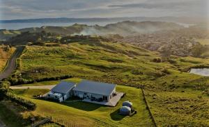 uma casa no topo de uma colina verde em Stunning Sunsets & Views at Wonderful Wainui em Gisborne