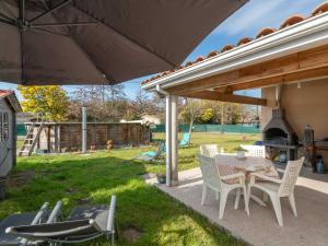 un patio avec une table et des chaises sous un parasol dans l'établissement Maison spacieuse à 600m du lac, 8 pers., piscine - FR-1-50-161, à Aureilhan