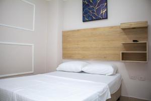 a white bed with two pillows in a room at HOTEL Gran rodadero HORIZON Santa Marta in Rodadero