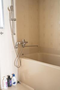 a bath tub with a shower in a bathroom at Vinyl Stay - spacious local apartment in Osaka