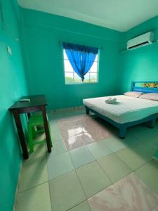 a bedroom with a bed and a table and a window at Zackry Guesthouse in Pantai Cenang +23 photos