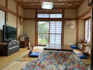 船引にある民宿とまとハウスTomato Houseのテーブルとテレビのあるリビングルーム