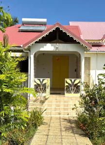 ein Haus mit einem roten Dach und einer gelben Tür in der Unterkunft Paradis Créole à Bellevue Sainte-Rose in Sainte-Rose