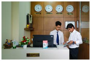 zwei Männer stehen an einem Schreibtisch in einem Büro in der Unterkunft Purple orchid in Bangalore