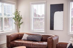 a brown leather couch in a living room with windows at Beach Retreat Complex w Pool - Sleeps 25 in Jacksonville Beach +95 photos
