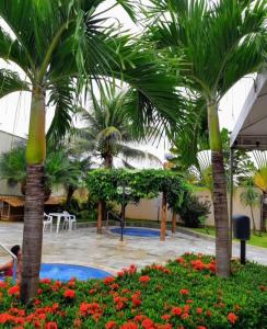 a courtyard with two palm trees and flowers at Apartamento 2 Quartos Caldas Novas in Caldas Novas