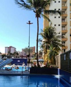 a swimming pool with palm trees and a hotel at Apartamento 2 Quartos Caldas Novas in Caldas Novas
