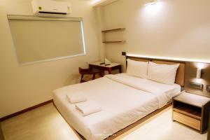 a bedroom with a white bed and a white board at Alite Enclaves Fully furnished apartments in Trichūr