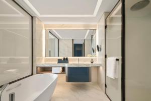 Bắc NinhにあるVinpearl Hotel Bắc Ninhの浴槽、洗面台、鏡のあるバスルーム +7枚の写真