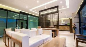 a living room with a white couch and some windows at L Hotel in Ban Si Than