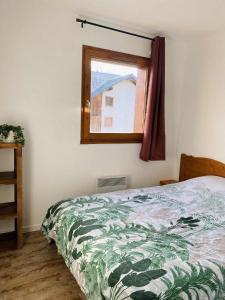 德沃吕伊Appartement super Devoluy的一间卧室，里面有一张床和一扇窗户。