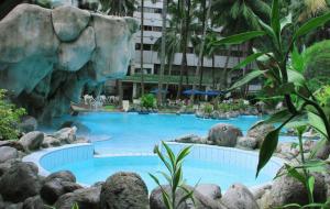 a large swimming pool in a resort with a waterfall at Danau Toba Hotel International in Medan