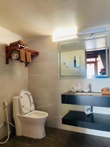 a bathroom with a toilet and a sink and a mirror at Ecohouse Hòn Sơn in Lai Sơn