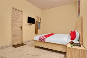 a bedroom with a bed with red pillows and a television at Hotel O Raas Near Hira Sweet in New Delhi +28 photos