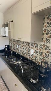 a kitchen with white cabinets and a black counter top at Casa da Gih in Penha