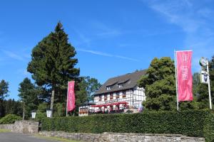 ヘレンタールにあるBoutique Hotel Restaurant Hollerather Hofのピンクの旗が目の前にある建物