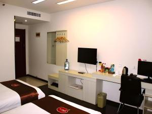 une chambre d'hôtel avec un lit et un bureau avec une télévision dans l'établissement Thank Inn Hotel Hebei Xingtai Shaheweisan Road Expressway Intersection, à Shahecheng