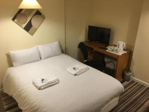 a hotel room with a bed and a television at The Tudor House Hotel in Nottingham