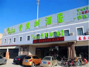 un edificio con coches estacionados frente a él en Vatica Tianjin Dagang Xuefu Road University Town Hotel, en Binhai