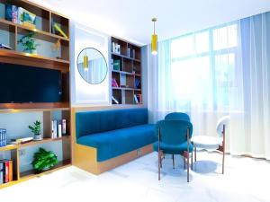 un salon avec un canapé bleu et une chaise dans l'établissement Magnotel Wulanhaote Hanshan Dong Street, à Ulan Hot