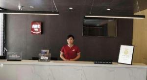 a man standing behind a counter in a restaurant at Thank Inn Plus Hotel Xinjiang Urumqi Tianshan District Bingtuan Erzhong in Ürümqi
