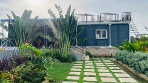 a blue house with a walkway in a garden at Aasa Farmhouse in Hyderabad