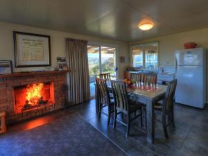 a dining room with a fireplace and a table and chairs at Arthur River Spa Cottage in Arthur River