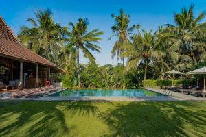 a resort swimming pool with palm trees in the background at Pertiwi Bisma Ubud in Ubud