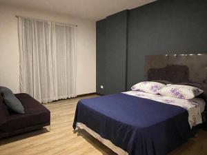a bedroom with a blue bed and a couch at Cómodo y acogedor departamento amoblado in Cochabamba