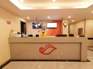 a man wearing a face mask stands behind a counter at a store at Shell Hotel Shanghai Jinshan Wanda Plaza in P'ai-ts'ang